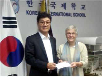 12월 29일 KIS에서 KEB하나은행 김상섭 홍콩지점장(왼쪽)이 린 톰슨 교장에게 학교 발전기금 5만 홍콩달러를 전달하고 있다.