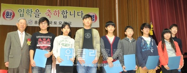 <성적우수 장학금을 받은 중.고등부 학생들이 장학금을 기부한 김진만 고문(왼쪽)과 함께 기념사진을 촬영하고 있다. >