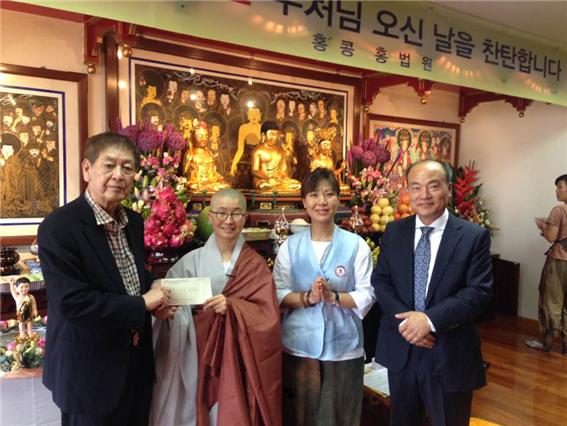 <홍법원 석지우 스님(왼쪽에서 두 번째)이 장자회 연임 회장(왼쪽)에게 금일봉을 전달하고 있다. >